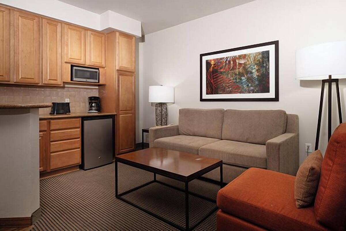 A compact living space with a kitchenette, a sofa, a coffee table, and a floor lamp.