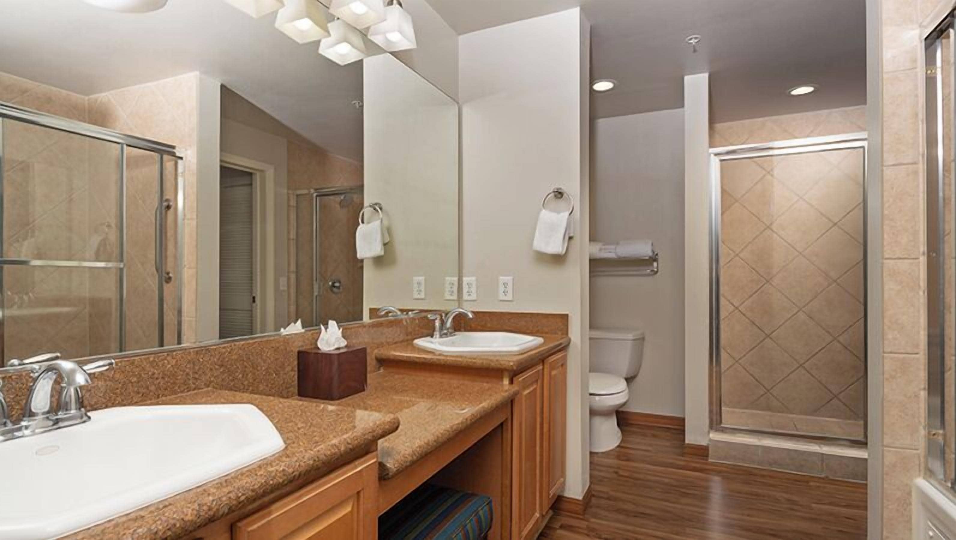 Une salle de bain moderne avec deux lavabos, un grand miroir et un espace douche.
