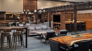 A modern hotel lobby with a dining area, sofas, and a bar. - Cleveland Marriott East (Warrensville Heights)