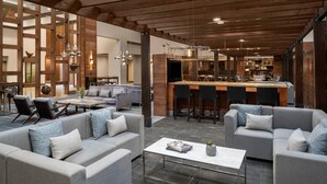 A spacious living area with sofas, a coffee table, and a bar area with stools. - Cleveland Marriott East (Warrensville Heights)