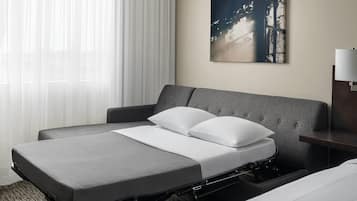 Een hotelkamer met een bed, nachtkastje, lamp en schilderij aan de muur.