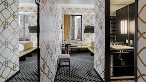 Une chambre d’hôtel comprenant un lit, un canapé, une petite table et une salle de bain avec un lavabo et un miroir.