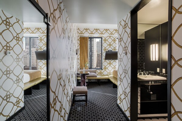 Une chambre d’hôtel comprenant un lit, un canapé, une petite table et une salle de bain avec un lavabo et un miroir.