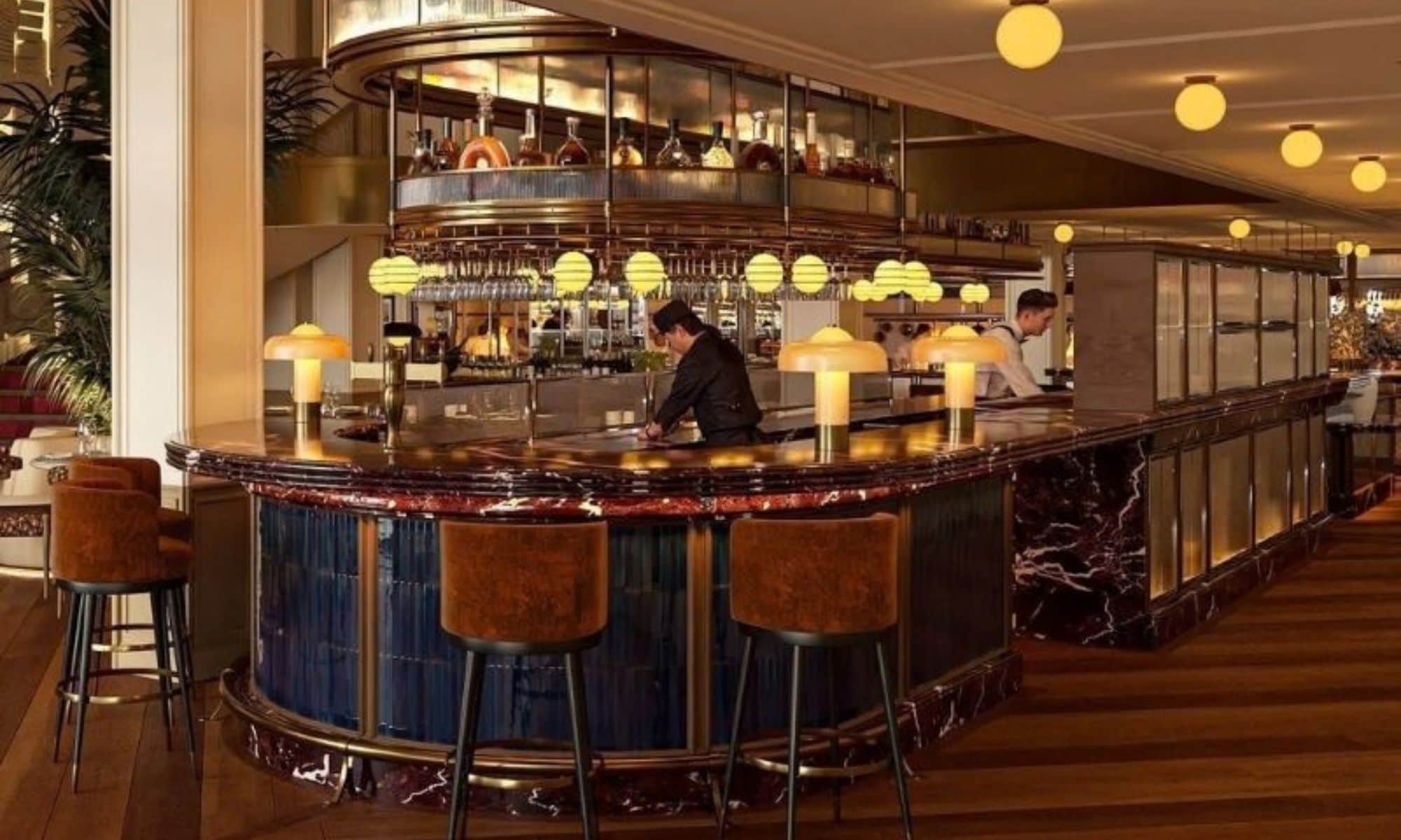 Un espace bar doté d’un comptoir incurvé, de tabourets de bar et d’un éclairage suspendu.