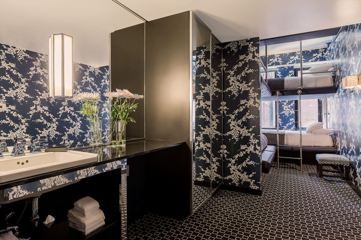 Un bagno moderno con carta da parati floreale in bianco e nero, un lavandino in vetro e uno specchio.