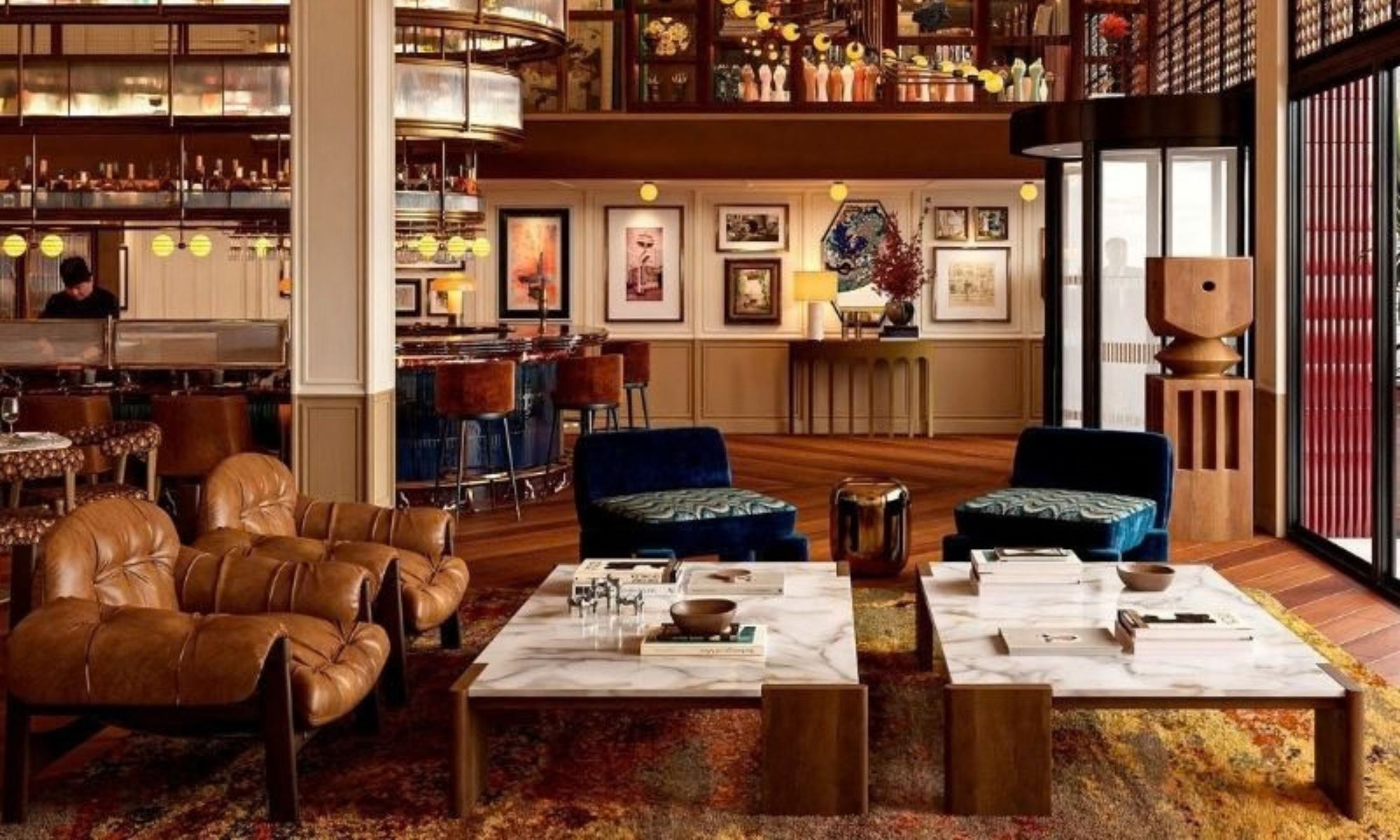 Un vaste espace salon agrémenté de canapés en cuir, d’une table basse en marbre et d’une bibliothèque remplie de livres et d’objets décoratifs.