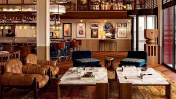 Un vaste espace salon agrémenté de canapés en cuir, d’une table basse en marbre et d’une bibliothèque remplie de livres et d’objets décoratifs.