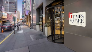 L’extérieur de l’hôtel 45 Times Square se distingue par son entrée en verre, son ascenseur visible et la vue dégagée qu’il offre sur la rue.