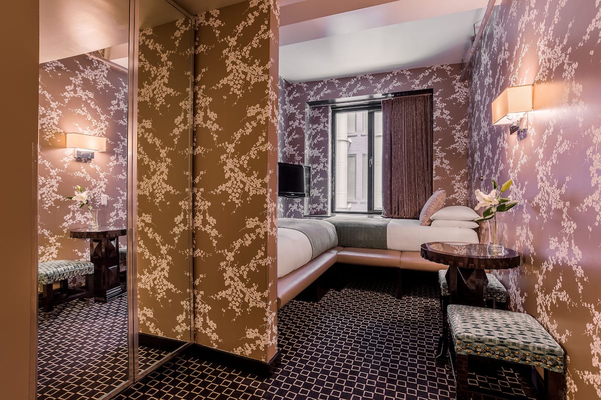 Una camera d'albergo con un letto, un'area salotto e un tavolino con un vaso di fiori.