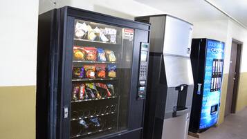 A vending machine with snacks and a drink dispenser in a hallway.