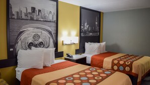 Een hotelkamer met twee bedden, een muurschildering van een stadsgezicht, een kleine tafel met een telefoon en een nachtkastje.