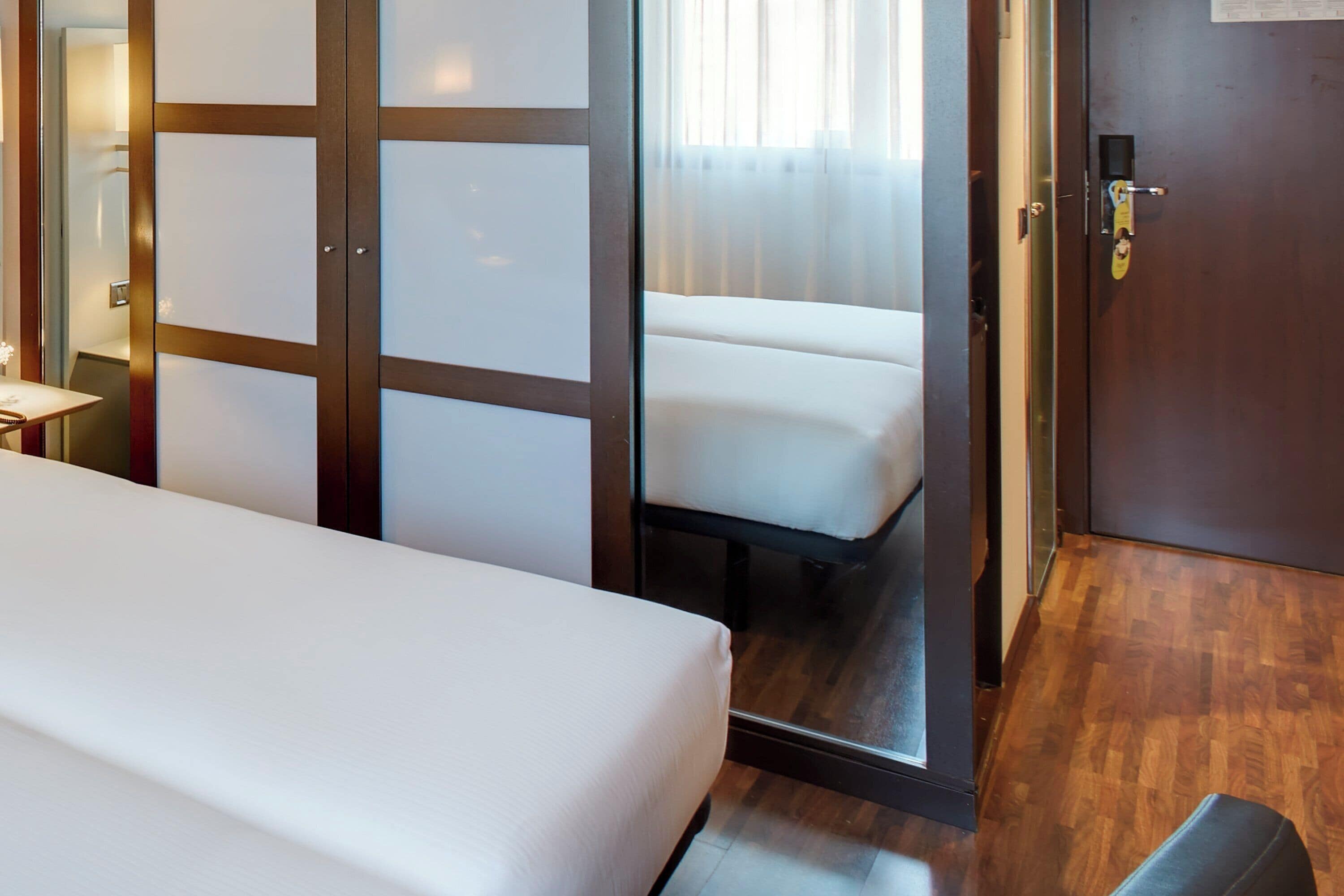 A hotel room with a bed, a seating area, and a door leading to a balcony.