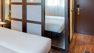 Ein Hotelzimmer mit einem Bett, einer Sitzecke und einer Tür, die auf einen Balkon führt.