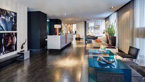 Una hall d'albergo moderna con reception, area relax e opere d'arte alle pareti.