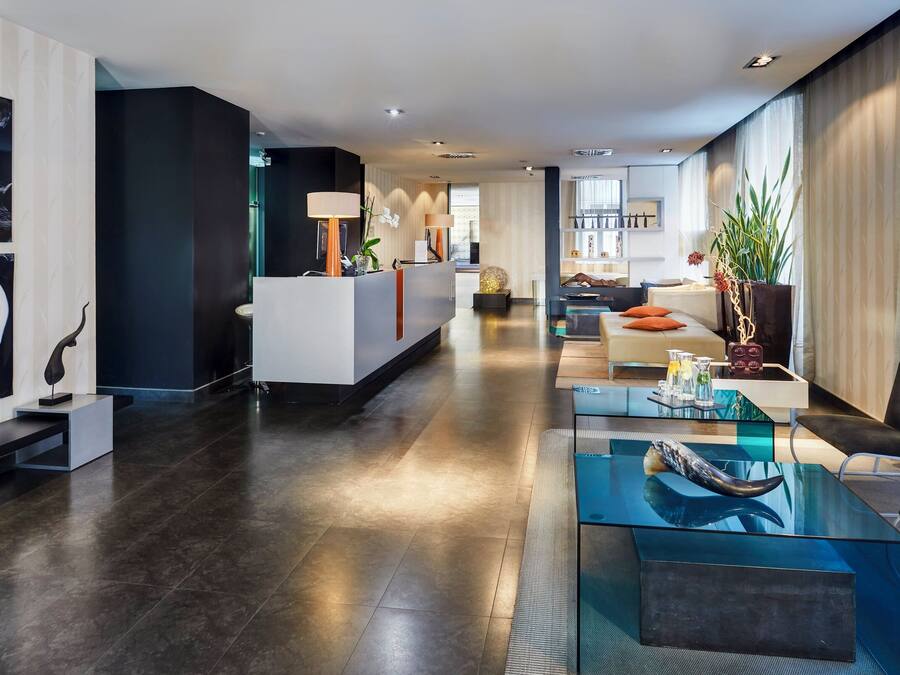 A modern hotel lobby with a reception desk, seating area, and artwork on the walls.