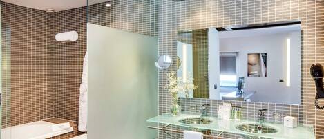 A modern bathroom with a glass sink, a large mirror, and a shower area.