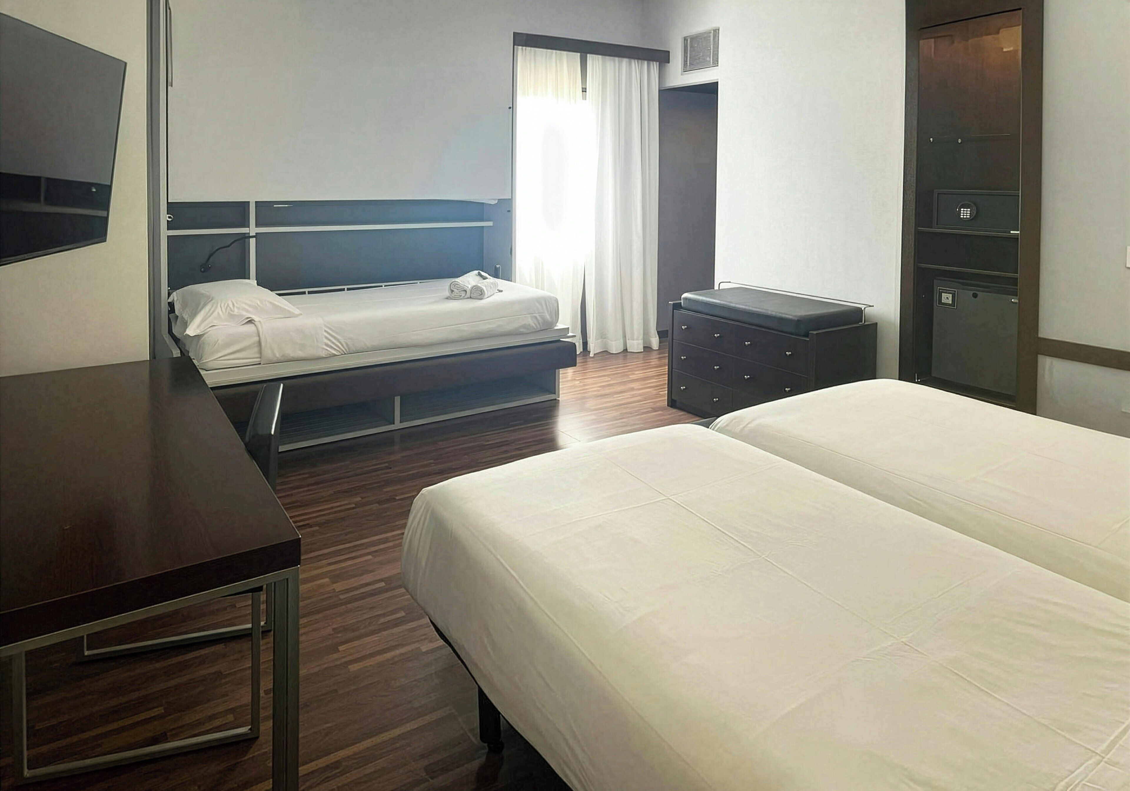 Une chambre d’hôtel comprenant un lit, un bureau, une commode et une armoire.