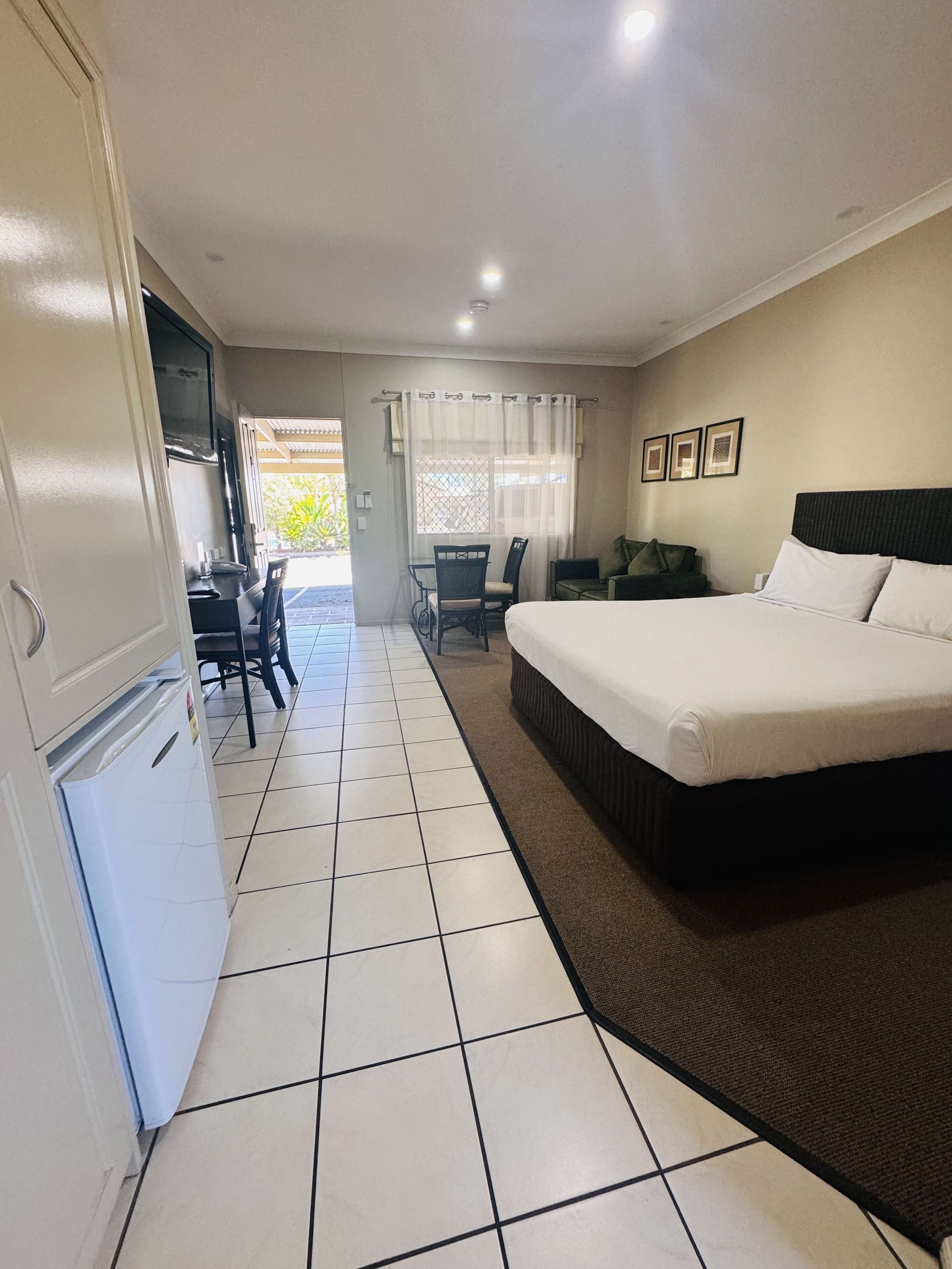 A hotel room with a bed, a desk, and a kitchenette.