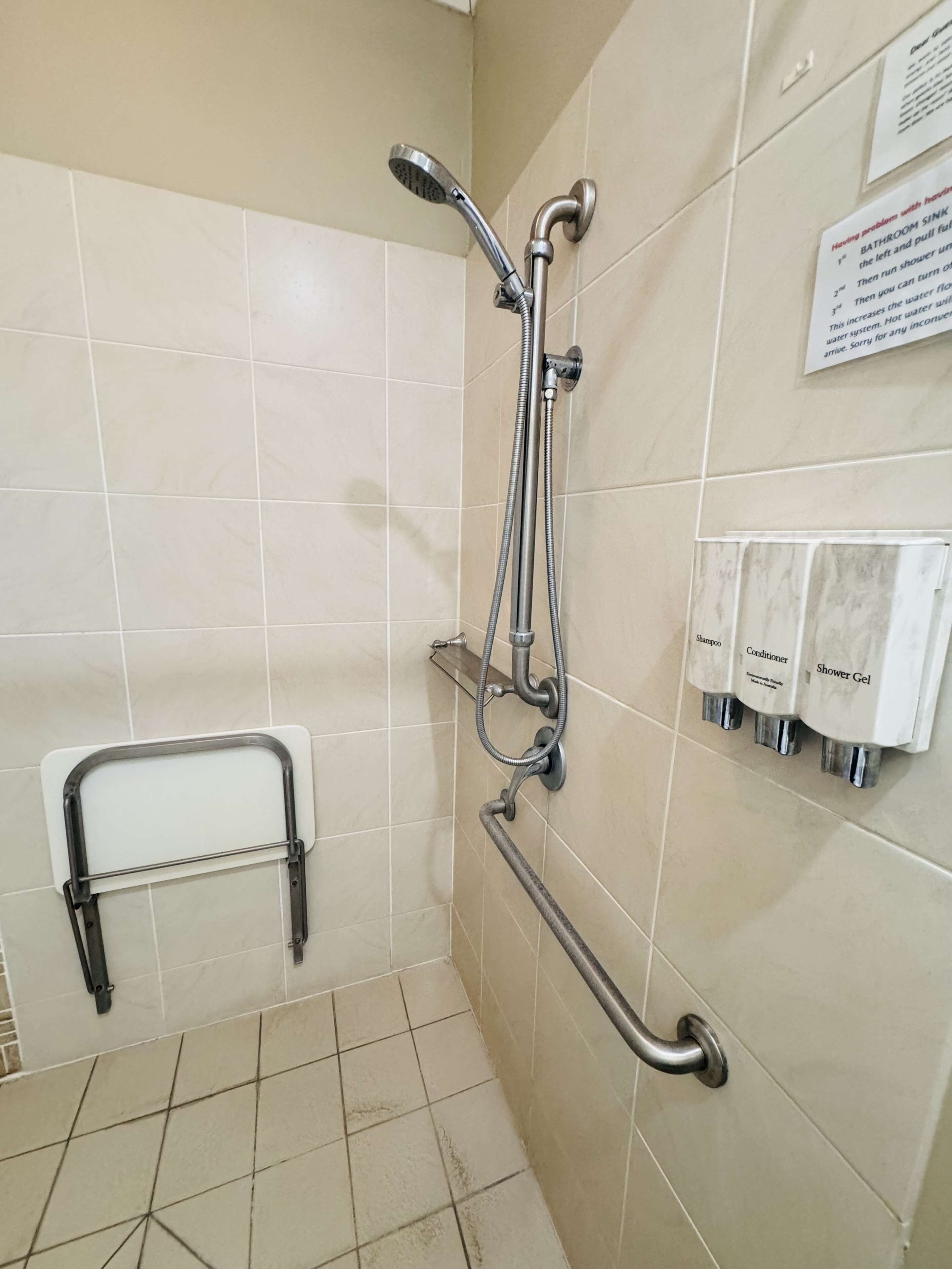 A bathroom with a shower, grab bars, and a sign with instructions.
