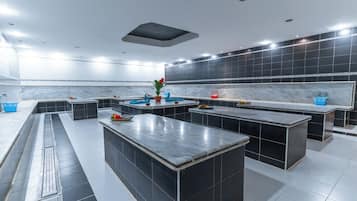 Una cocina moderna con paredes de baldosas blancas y negras, varias estaciones de trabajo y una isla central con una planta.