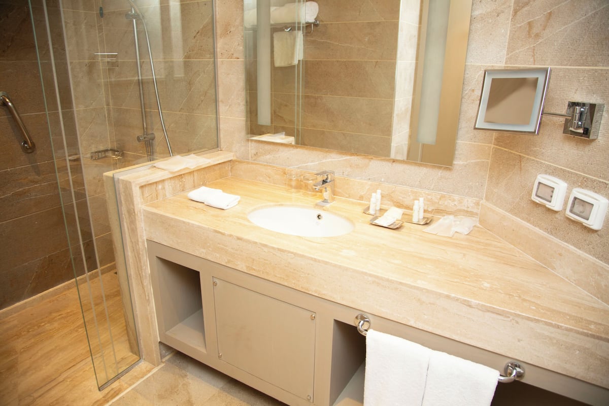 A modern bathroom with a glass-enclosed shower, a large sink, and a mirror.