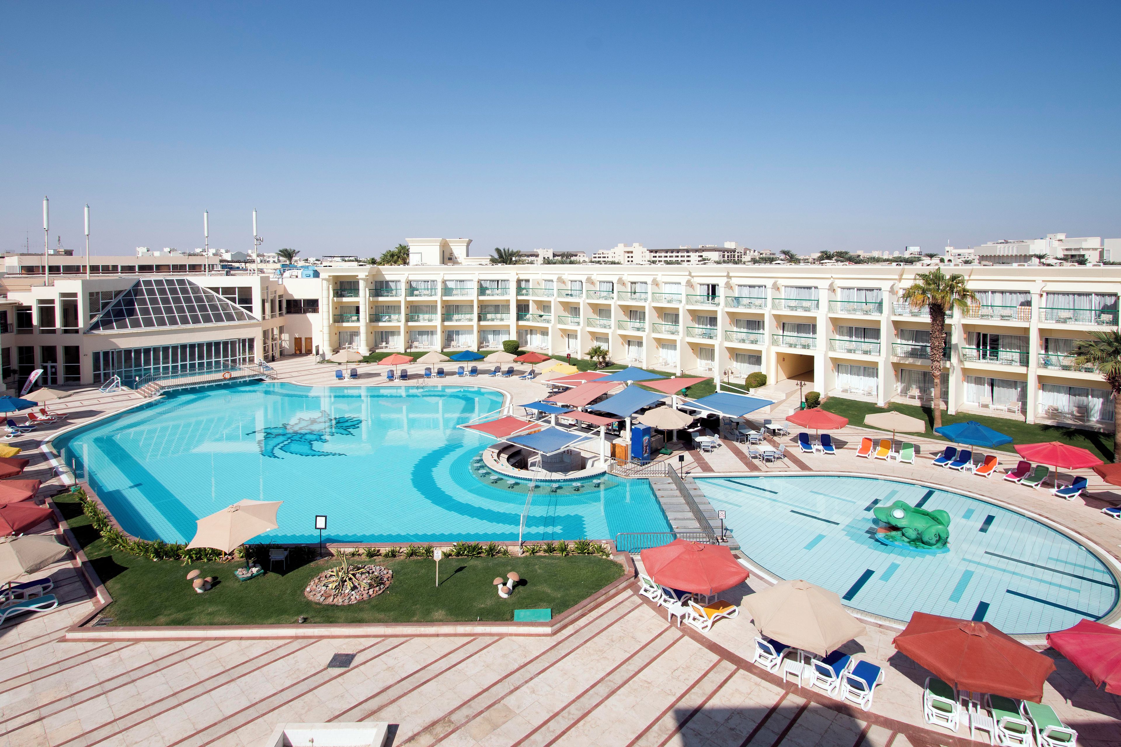 A hotel with a large central pool, multiple balconies, and outdoor seating areas.