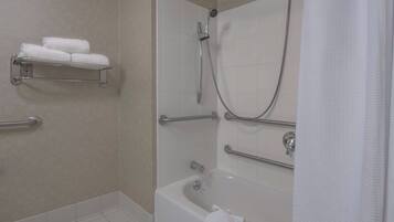 A bathroom with a walk-in shower, grab bars, a towel rack with towels, and a bathtub.