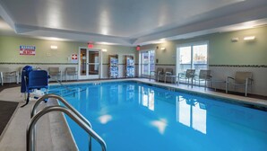 En swimmingpool med en livredderstol, stole rundt om poolen, og et skilt der advarer om, at der ikke er livredder til stede.