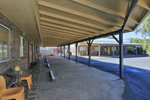 Un espacio de estar al aire libre cubierto con mesas y sillas, un edificio de ladrillo y una vista despejada de la calle.