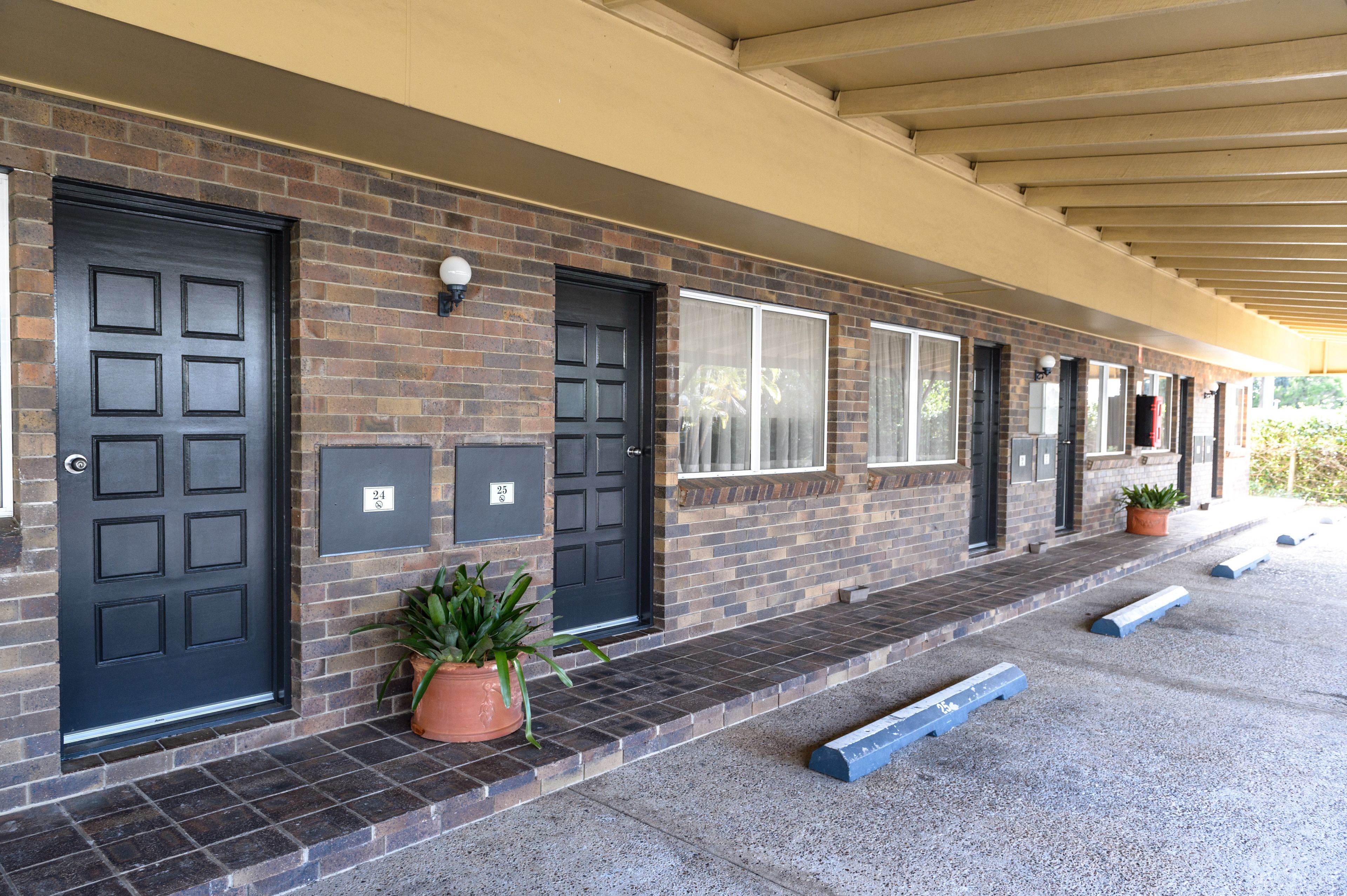 A building with a brick facade, black doors, and a covered walkway.
