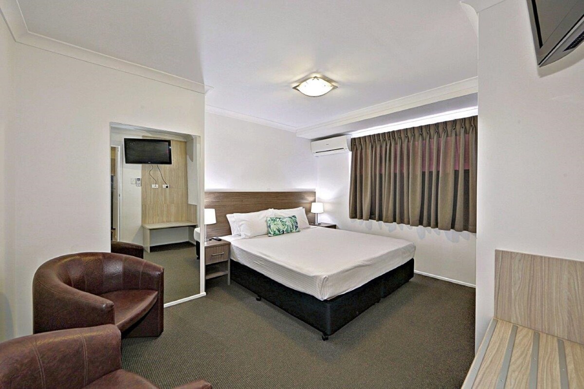 Ein Hotelzimmer mit Bett, Fernseher, Schreibtisch und Stuhl.