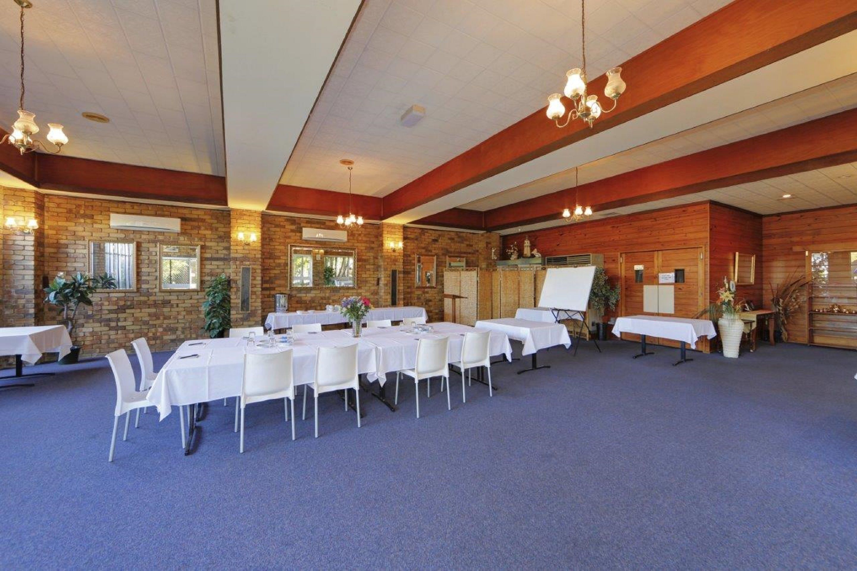 A spacious indoor area with multiple tables and chairs, wooden walls, and hanging lights.