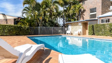 Una piscina al aire libre, sillones reclinables de piscina