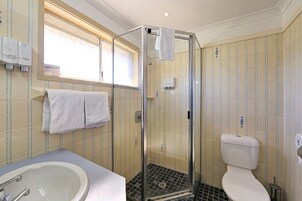 A bathroom with a glass-enclosed shower, a toilet, and a sink.