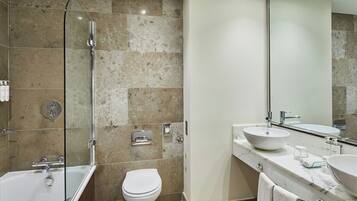 Un baño moderno con bañera, inodoro y un espejo grande.