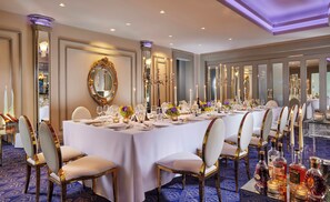 A formal dining room with a long table set for a meal, surrounded by chairs with gold accents. - The G Hotel and Spa (Galway)