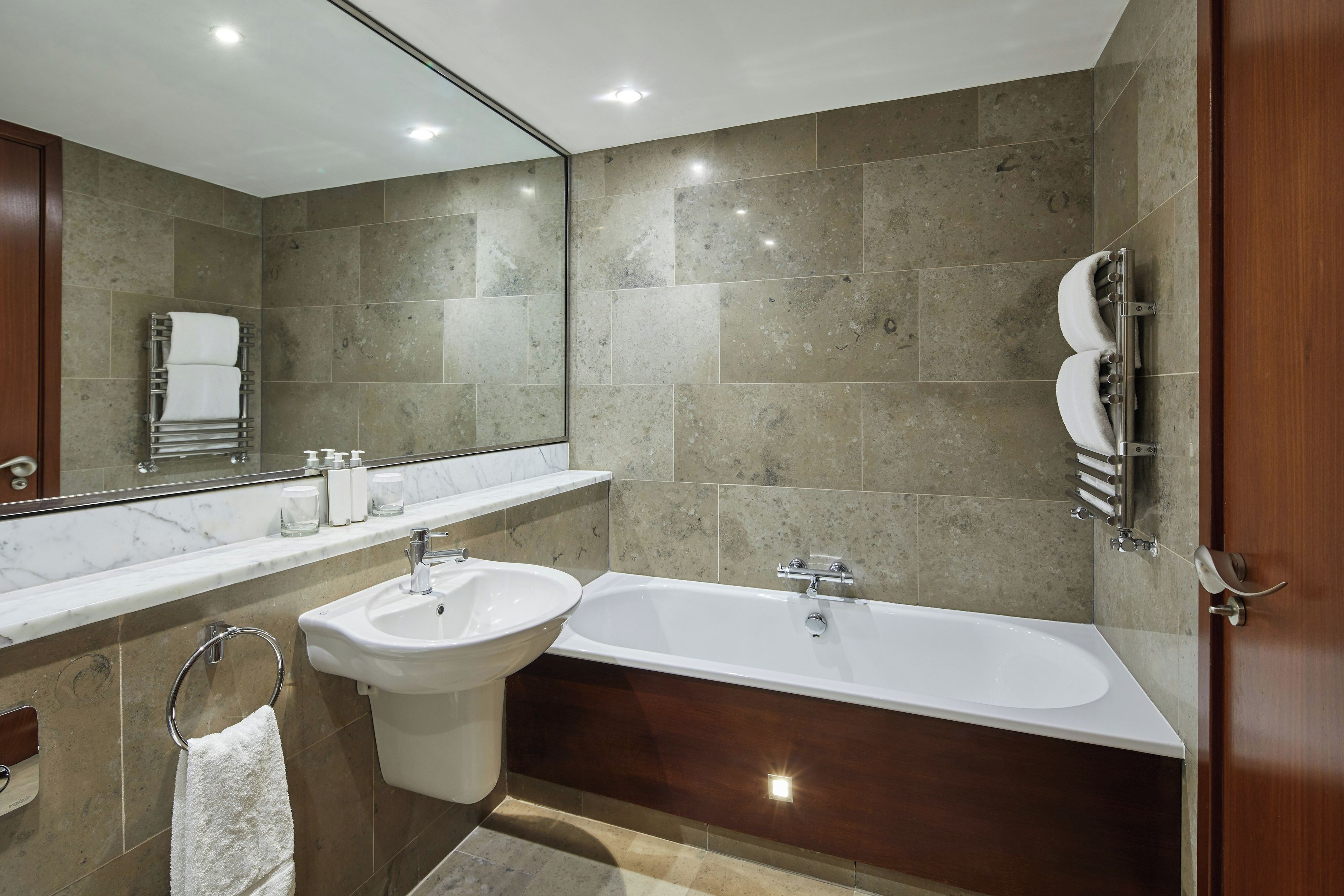 Un baño moderno con bañera, dos lavamanos y un espejo grande.