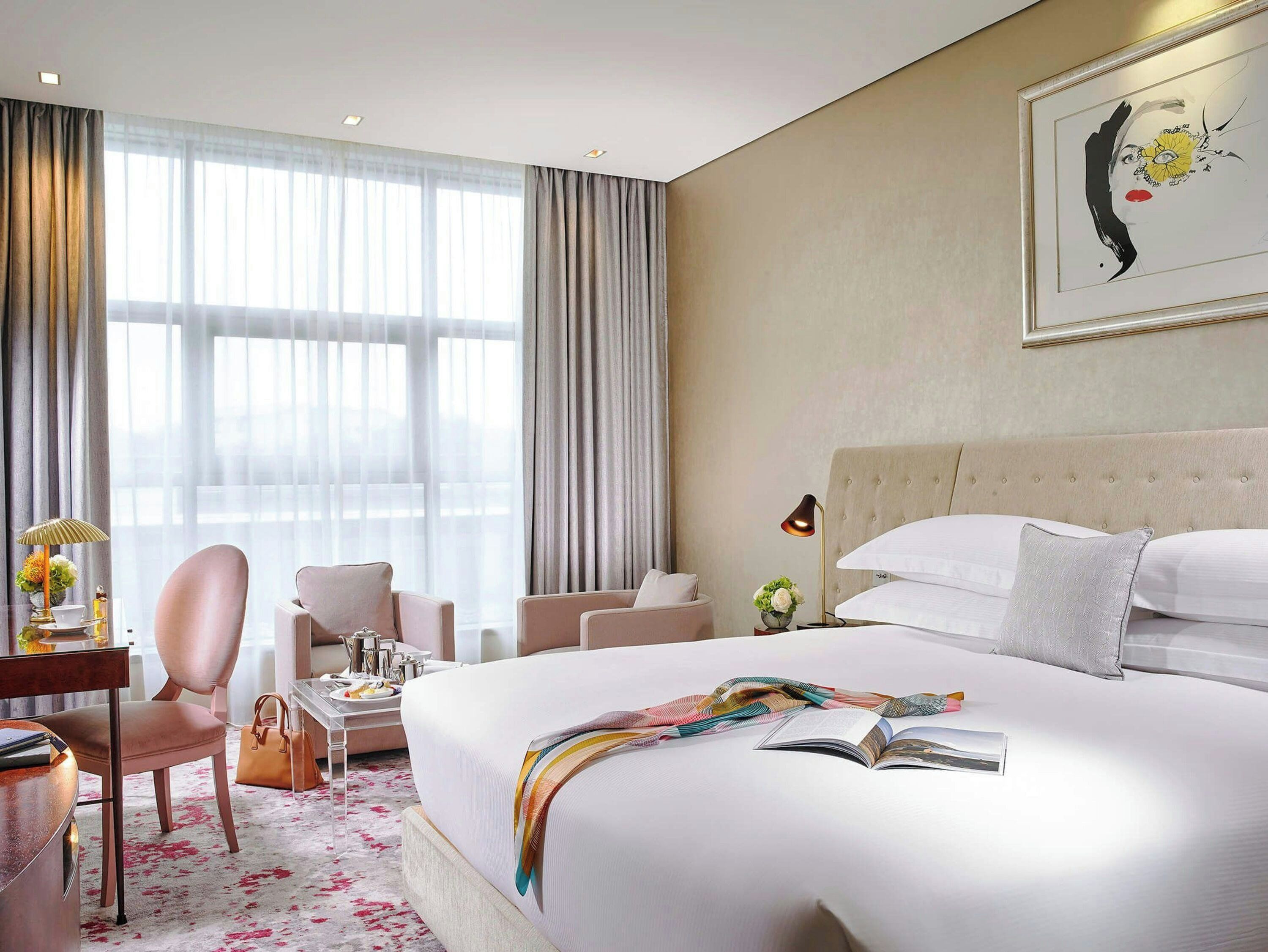 Une chambre d’hôtel avec un grand lit, un bureau avec une chaise, une lampe et un tableau au mur.