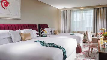 A hotel room with two beds, a desk, a chair, and a large window with curtains.