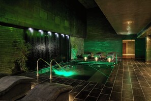 A spa area with a hot tub, seating, and a wall with water features. - The G Hotel and Spa (Galway)
