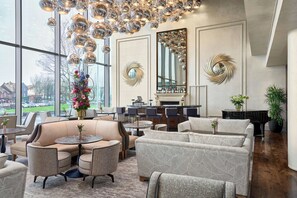 A spacious lounge area with leather sofas, round tables, and a large chandelier. - The G Hotel and Spa (Galway)
