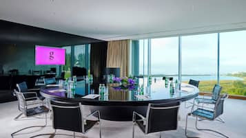 A modern conference room with a glass table, black chairs, and a view of the outdoors.