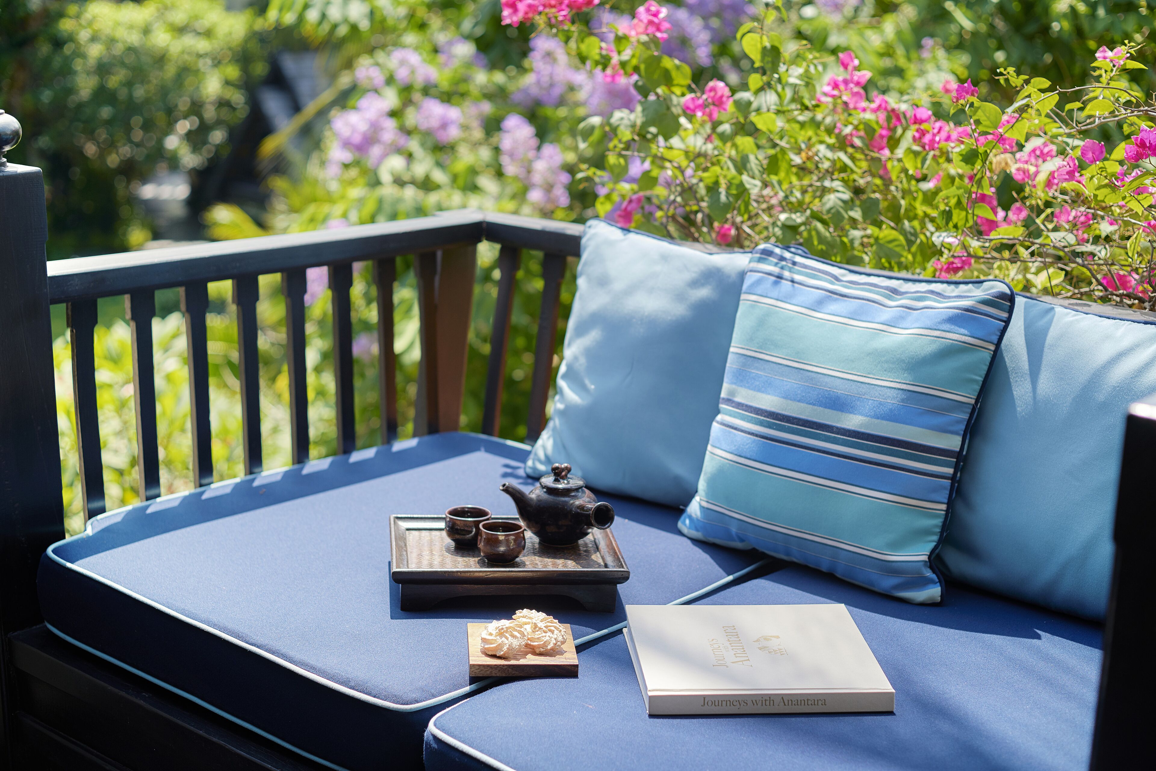 A blue outdoor seating area with a tray of tea and a book titled "Journeys with Anita".