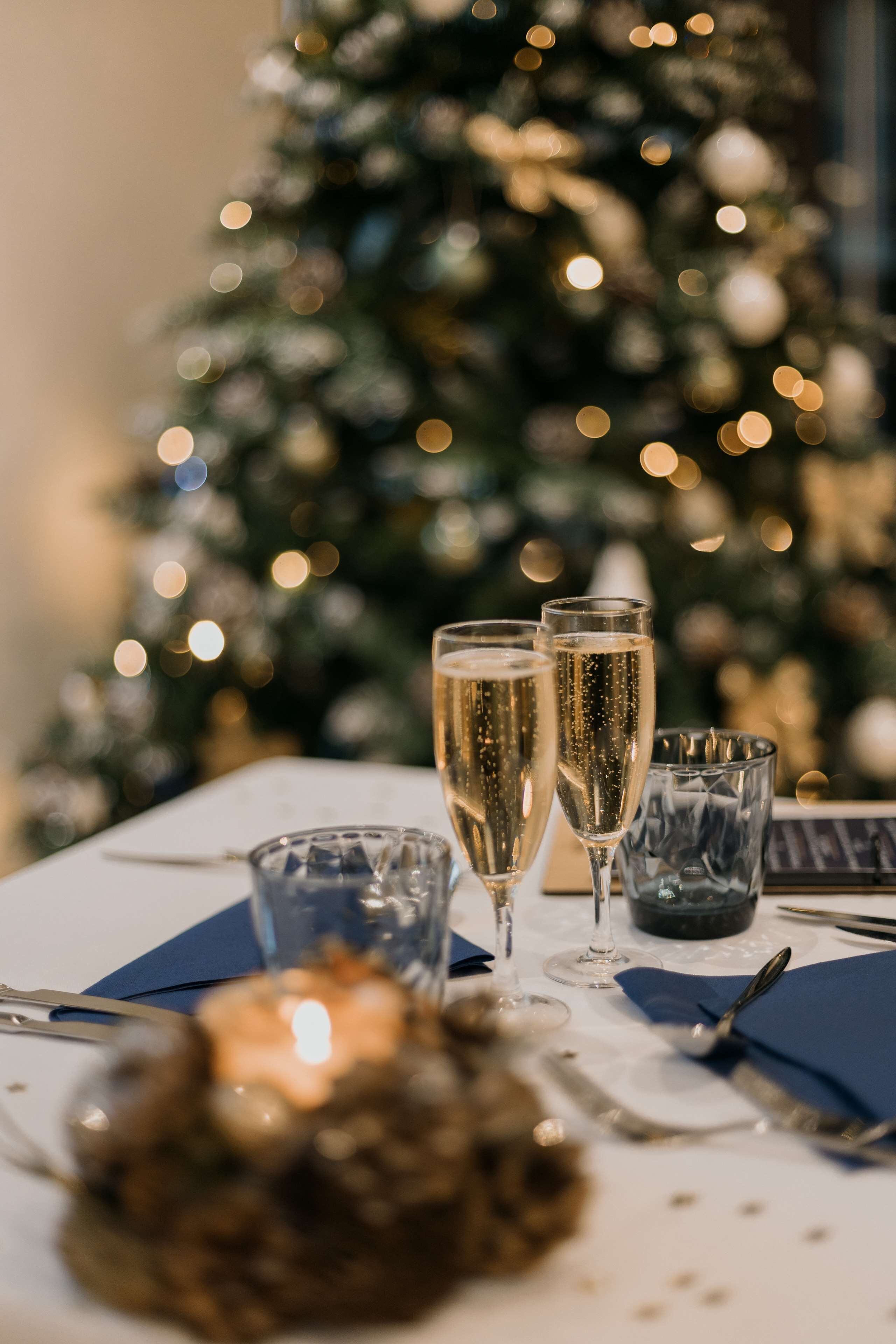 Una mesa dispuesta para una comida, con un árbol de Navidad al fondo.