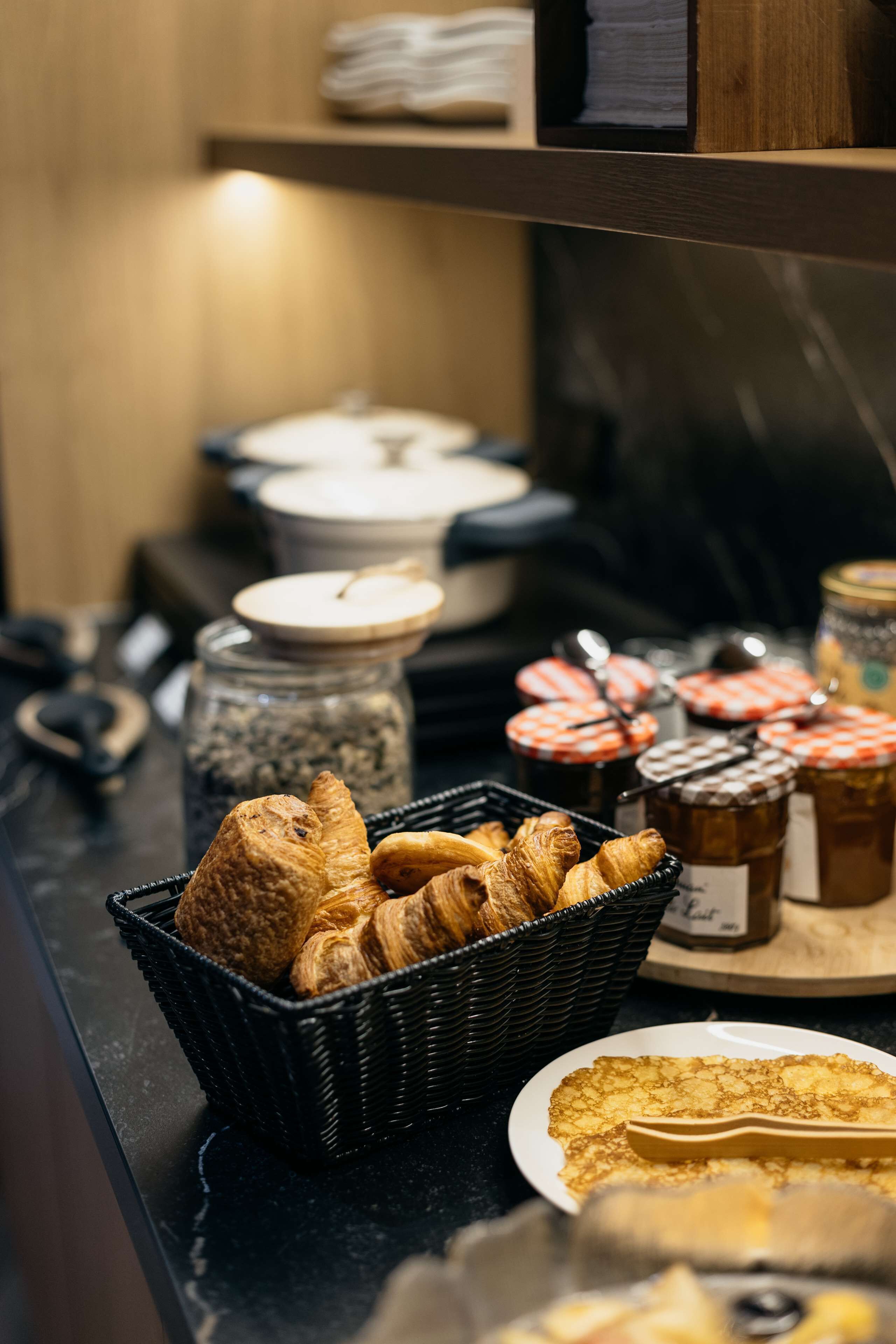 A breakfast buffet with croissants, jams, and other pastries.