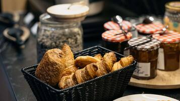 A breakfast buffet with croissants, jams, and other pastries.