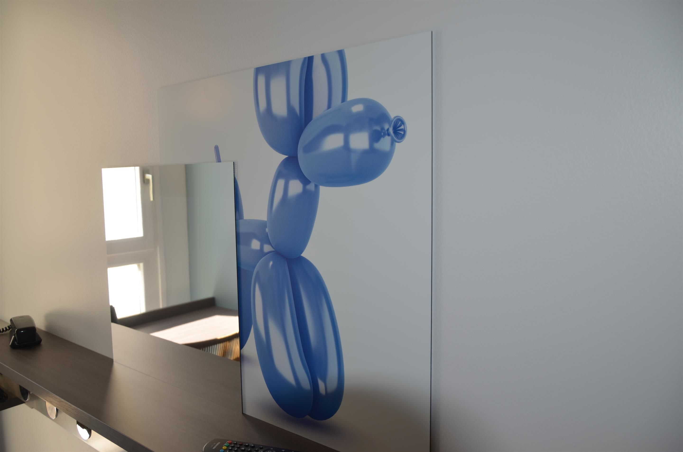 Un bagno con un grande specchio, un lavandino e un quadro astratto blu appeso al muro.