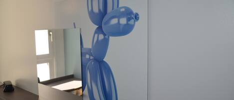 A bathroom with a large mirror, a sink, and a blue abstract painting on the wall.