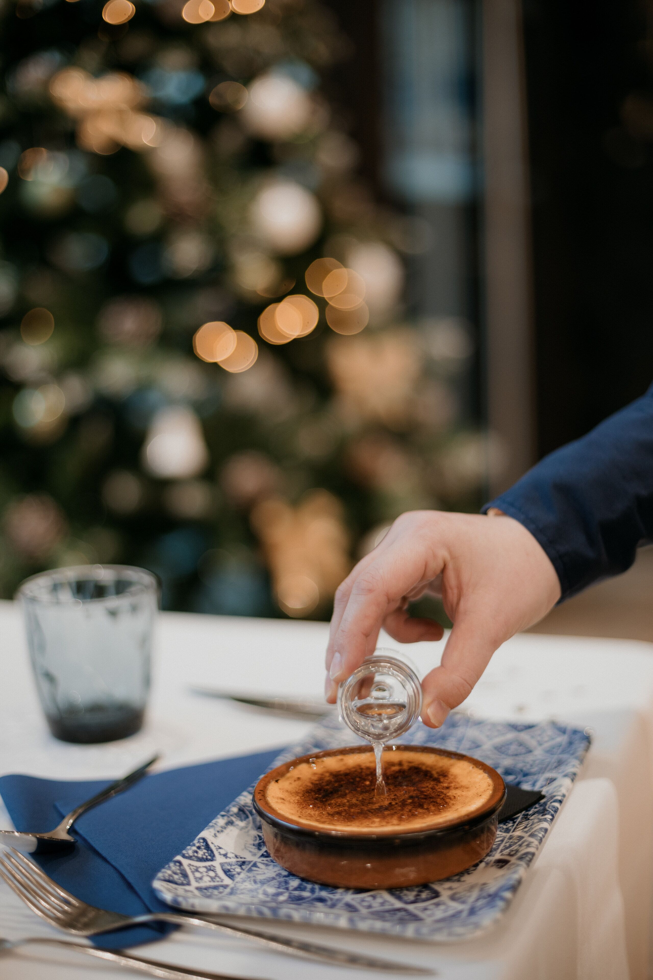 Een dessert op een bord met een blauw-wit patroon, een vork en een glas op een tafel.