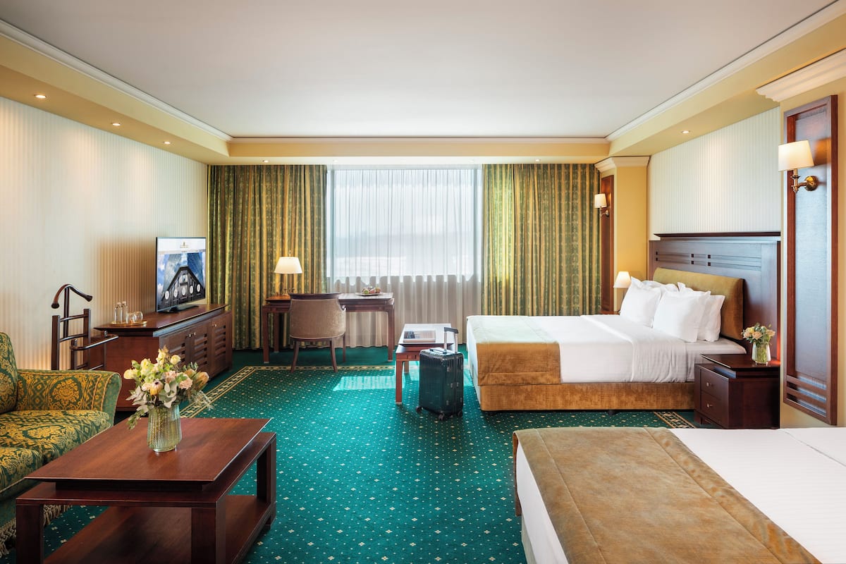 A hotel room with a large bed, a desk with a chair, a TV, and a decorative vase.